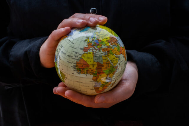 Globus w dłoniach na ciemnym tle.